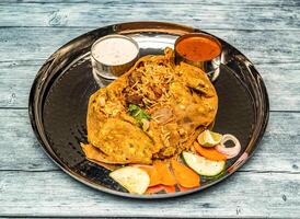 darbar Koninklijk potlam biryani rijst- inpakken met raita en Chili saus geserveerd in schotel geïsoleerd Aan houten tafel top visie van Indisch pittig voedsel foto