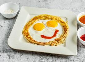 emoji paratha met zonnig ei, chili en tomaat saus en mayo dip geserveerd in schotel geïsoleerd Aan achtergrond top visie van desi Indisch voedsel foto