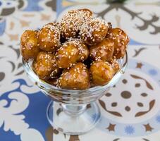 luqaimat of gemat zoet ballen met sesam zaden geserveerd in schotel geïsoleerd Aan tafel top visie van Arabisch toetje voedsel foto