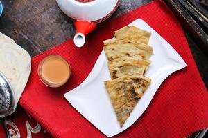 pittig arayen met koffie kop en theepot geserveerd in schotel geïsoleerd Aan rood mat top visie Aan tafel Arabisch voedsel foto