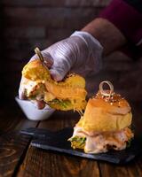 gevuld kip hamburger Holding in hand- met gesmolten kaas, kip, sla bladeren en ei geserveerd in schotel geïsoleerd Aan houten tafel kant visie van Arabisch voedsel foto