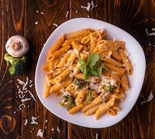 pasta met broccoli, paddestoel en munt bladeren geserveerd in schotel geïsoleerd Aan houten tafel top visie van Arabisch voedsel foto