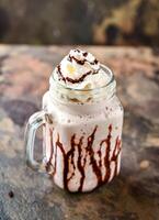 Californië dromen milkshake met ijs room, chocola en geslagen room geserveerd in pot geïsoleerd Aan donker achtergrond kant visie van gezond drinken foto