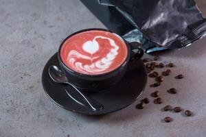 heet biet latte kunst portie in koffie kop met lepel en bonen kant visie Aan grijs achtergrond foto