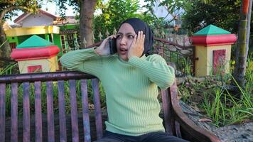 geschokt Aziatisch moslim vrouw pratend Aan mobiel telefoon in park, vrij ruimte foto