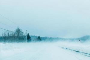 gekke sneeuwstorm en waaiende sneeuw op de weg in canada foto