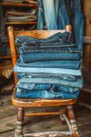 denim dagen stack van blauw jeans Aan rustiek houten stoel foto