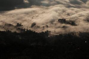 cloudscape wonderland, berg pieken bovenstaand wolken, betoverend Woud hieronder foto