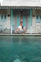 zwembad rust, Aziatisch model- in lotus yoga houding, Bali villa ontspanning foto