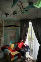 Aziatisch Mens werken Aan laptop in zonovergoten villa, sofa comfort, produktiviteit foto