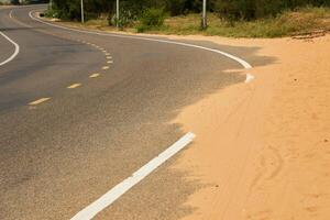 woestijn zand stappen Aan een asfalt weg. foto