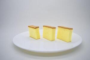 drie plakjes van kaas taart Aan een wit bord met een duidelijk achtergrond foto