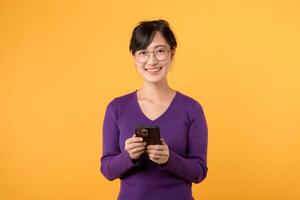 portret jong Aziatisch vrouw Jaren 30 vervelend Purper overhemd met bril gelukkig glimlach gebruik makend van smartphone chatten. elke dag gebruik mobiel telefoon concept. foto