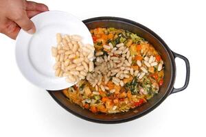 Toscaans ribollita soep stap door stap met wit bonen, selderij, snijbiet, uien en olijf- olie foto