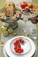 bord met tomaten Aan tafel met panettone, bril, fruit en wijn foto