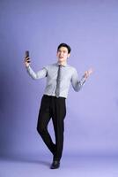 portret van Aziatisch mannetje zakenman staand en poseren Aan Purper achtergrond foto