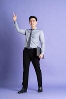 portret van Aziatisch mannetje zakenman staand en poseren Aan Purper achtergrond foto