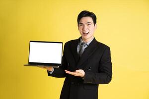 portret van Aziatisch mannetje zakenman. vervelend een pak en poseren Aan een geel achtergrond foto