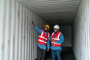 portret van twee Afrikaanse ingenieur of voorman draagt ppe controle houder opslagruimte met lading houder achtergrond Bij zonsondergang. logistiek globaal importeren of exporteren Verzending industrieel concept. foto