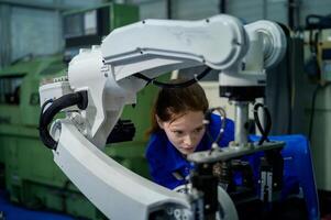 vrouw robotica ingenieur werken met programmering en manipuleren robot hand, industrieel robotica ontwerp, hoog tech faciliteit, modern machine aan het leren. massa productie automaten. foto