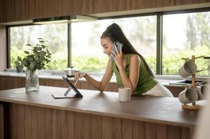 jong Aziatisch vrouw werken met tablet in de keuken Bij huis foto