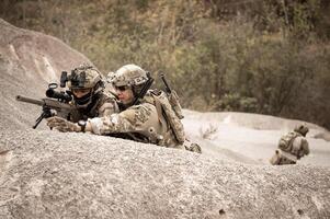 soldaten in camouflage uniformen het richten met hun geweren gereed naar brand gedurende leger operatie in de woestijn soldaten opleiding in een leger operatie foto