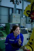 vrouw robotica ingenieur werken met programmering en manipuleren robot hand, industrieel robotica ontwerp, hoog tech faciliteit, modern machine aan het leren. massa productie automaten. foto