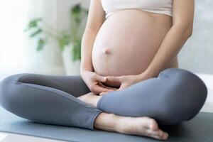 zwanger vrouw aan het doen yoga Aan oefening mat. mediteren voor korte termijn bevalling van mediteren aantrekkelijk zwanger vrouw recreatie en kom tot rust, ademen en kalmte met yoga. zelf zorg foto