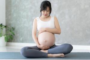 zwanger vrouw aan het doen yoga Aan oefening mat. mediteren voor korte termijn bevalling van mediteren aantrekkelijk zwanger vrouw recreatie en kom tot rust, ademen en kalmte met yoga. zelf zorg foto