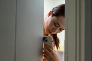 de Aziatisch meisje verborg achter de deur in angst foto