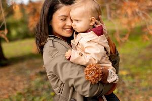 jong vrouw Holding schattig baby meisje in de herfst park foto