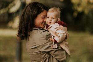 jong vrouw Holding schattig baby meisje in de herfst park foto