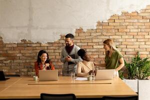 jong multi-etnisch opstarten team werken door de steen muur in de industrieel stijl kantoor foto