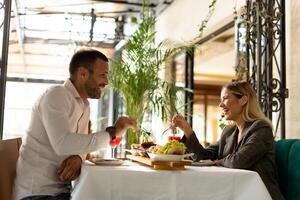 jong paar hebben lunch en drinken vers geperst sap in de restaurant foto