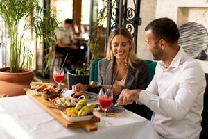 jong paar hebben lunch en drinken vers geperst sap in de restaurant foto