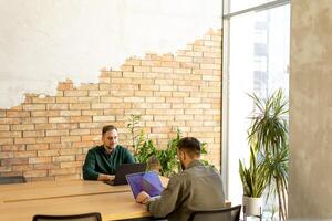 samenwerking in beweging, professionals werken samen in een modern met bakstenen muren kantoor foto