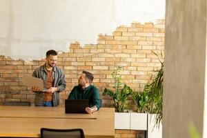 samenwerking in beweging, professionals werken samen in een modern met bakstenen muren kantoor foto