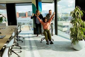 jubelend kantoor viering vangt collega's spontaan stoel ras in zonovergoten kamer foto