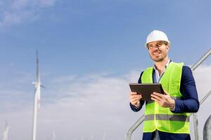 glimlachen ingenieur met tablet inspecteren wind turbines Aan een zonnig dag foto