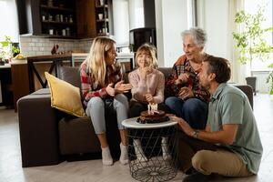 vreugdevol familie vieren grootmoeders verjaardag met taart in een knus leven kamer foto