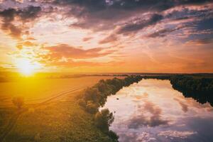 een zonsondergang of zonsopkomst tafereel over- een meer of rivier- met bewolkt luchten reflecterend in de water Aan een zomer avond of ochtend. esthetiek van wijnoogst film. foto