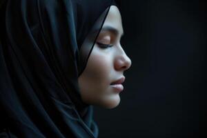 een moslim vrouw met Gesloten ogen Aan een zwart achtergrond. Arabisch meisje in hijab in profiel. foto