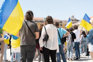 Portugal, Lissabon april 2022 de demonstratie Aan handel plein in ondersteuning van Oekraïne en tegen de Russisch agressie. demonstranten tegen Rusland oorlog veel mensen met oekraïens vlaggen. foto
