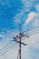takken van oud elektriciteit polen Aan een bewolkt blauw lucht achtergrond foto