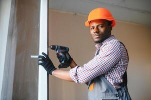 knap jong Afrikaanse Amerikaans Mens installeren baai venster in nieuw huis bouw plaats foto