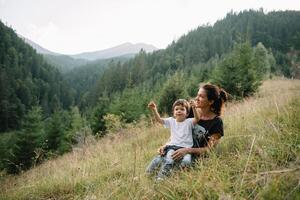 jong mam met baby jongen reizend. moeder Aan wandelen avontuur met kind, familie reis in bergen. nationaal park. wandeltocht met kinderen. actief zomer vakantie. vissenoog lens. foto