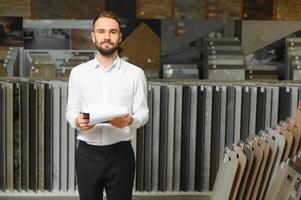 portret van een keramisch tegel verkoper. de verkoper staat tegen de achtergrond van een groot assortiment van tegels foto