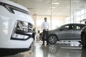 portret van knap Afrikaanse Amerikaans verkoper Bij werkplaats in auto toonzaal foto