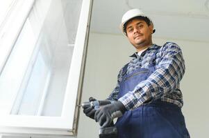 Indisch bouw arbeider installeren venster in huis. foto