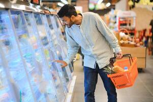 portret van knap jong Indisch Mens staand Bij kruidenier winkel of supermarkt, detailopname. selectief focus. foto